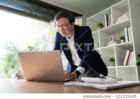 Elderly businessman working on laptop for financial planning and management. Elderly businessman working on laptop for financial planning and management. 122335105
