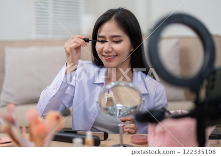 Beauty broker expertly applying mascara while showcasing cosmetics during a live broadcast Beauty broker expertly applying mascara while showcasing cosmetics during a live broadcast 122335108