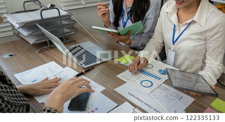 Diverse team analyzing data charts and discussing strategies during a focused business meeting in a modern office Diverse team analyzing data charts and discussing strategies during a focused business meeting in a modern office 122335133