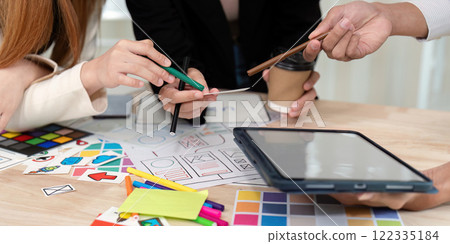 Collaborative UX UI team examining design notes and sketches while engaging in a creative discussion 122335184