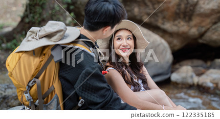 LGBT couple enjoying a playful conversation by a serene stream during their hike LGBT couple enjoying a playful conversation by a serene stream during their hike 122335185