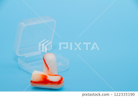 淺藍色背景上的橘色耳塞 淺藍色背景上的橘色耳塞 122335190