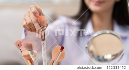 Beauty broker showcasing makeup brushes during a live broadcast session 122335452