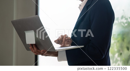 Elderly professional using laptop for business insights and digital strategy. Elderly professional using laptop for business insights and digital strategy. 122335500
