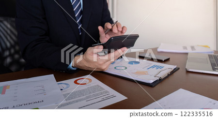 Accountant calculating financial projections using a calculator while reviewing reports in a modern office 122335516