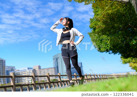 一個酷女人走在河邊人行道上，舉起手，飲食，散步，鍛煉 122336041