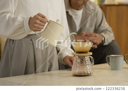 Middle-aged woman brewing coffee in the living room at night, no face 122336238