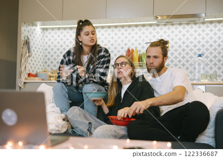 A Group of Friends Relishing an Enjoyable Movie Night Together with Snacks at Home 122336687