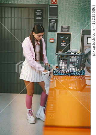A Trendy Young Woman Enjoying Herself at a Bright and Modern Laundry Room Facility A Trendy Young Woman Enjoying Herself at a Bright and Modern Laundry Room Facility 122336862