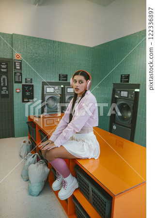 A Young Woman Enjoying Music at a Modern Laundry While Wearing Headphones and Relaxing 122336897