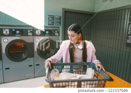 A Young Woman Happily Doing Laundry in a Bright and Modern Laundromat Environment A Young Woman Happily Doing Laundry in a Bright and Modern Laundromat Environment 122337086