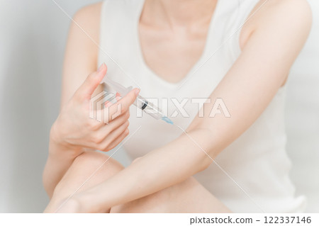 A woman hitting her arm with a stimulant, drug, or illegal drug with a syringe 122337146