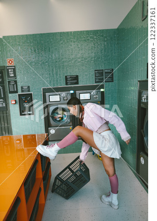 A Young Woman Engaged in Activities Within a Laundry Room While Handling a Laundry Basket 122337161