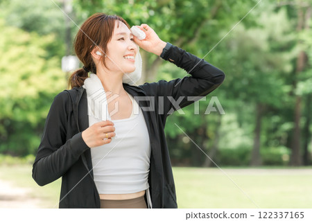 Woman running, walking, jogging, exercising (diet, sports) with earphones in the park 122337165