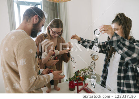Family members joyfully celebrating together indoors, surrounded by festive holiday decorations 122337180