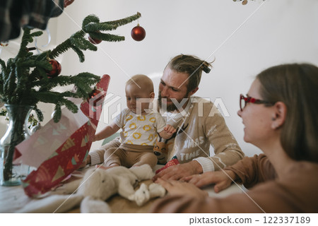 A joyful family gathered together for a festive Christmas celebration with their baby and gifts A joyful family gathered together for a festive Christmas celebration with their baby and gifts 122337189