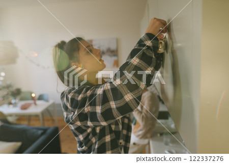 A woman is decorating a wall in her cozy living room, creating a warm and inviting ambiance 122337276