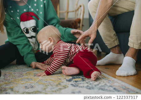 A joyful crawling baby enjoys time with family in a cozy holiday setting full of cheer 122337317