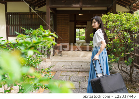 A young woman pulling a suitcase and returning to the countryside Travel image 122337440