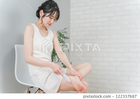 微笑的亞洲女人用腳後跟上的銼刀做足部護理 122337687