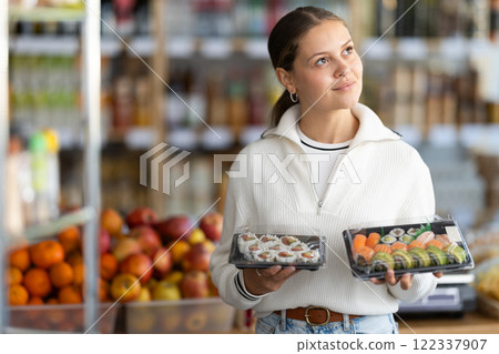 Young woman choosing packaged sushi and rolls 122337907