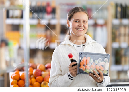 Grocery shopping at supermarket - woman chooses soy sauce for sushi Grocery shopping at supermarket - woman chooses soy sauce for sushi 122337929