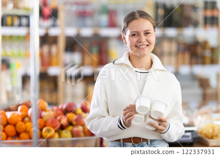 Woman chooses tasty yogurt to buy in the grocery department section of store Woman chooses tasty yogurt to buy in the grocery department section of store 122337931