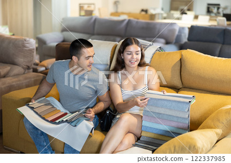 In exhibition hall,couple sat down on sand-colored sofa and keep sets of upholstery material samples In exhibition hall,couple sat down on sand-colored sofa and keep sets of upholstery material samples 122337985