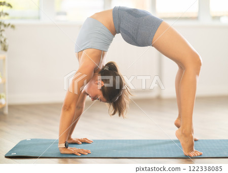 Young woman practicing yoga in urdhva dhanurasana pose 122338085