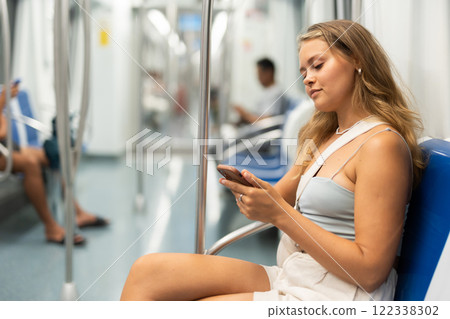 Young girl sitting in wagon holding mobile phone in hand Young girl sitting in wagon holding mobile phone in hand 122338302