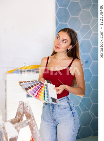 Beautiful young woman choosing tiles color samples in apartment 122338486
