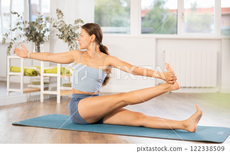 Lover of active lifestyle on yoga mat perform doing eka padahastasana salamba navasan in gym 122338509