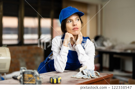 Woman construction worker posing inside house under renovation Woman construction worker posing inside house under renovation 122338547