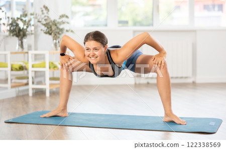 Young woman performing Parivrtta Utkata Konasana in yoga studio Young woman performing Parivrtta Utkata Konasana in yoga studio 122338569
