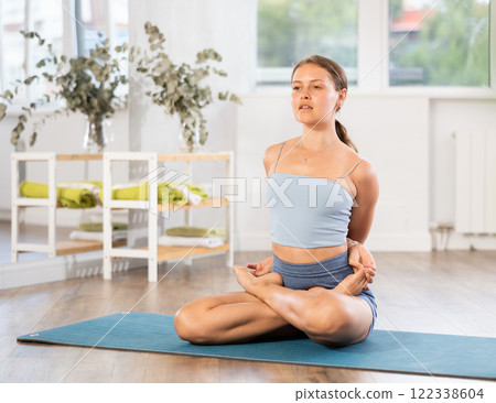 Lover of active lifestyle on yoga mat perform doing variations of padmasan in gym 122338604