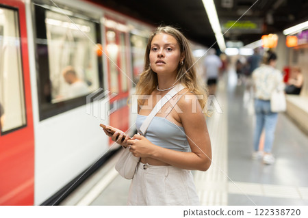 Young woman with phone stands at metro station Young woman with phone stands at metro station 122338720