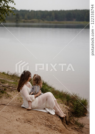 Mother and child sitting by a lake.  122338744