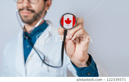 Doctor holding stethoscope with Canada flag. Canadian Health and Care Concept, Canada flag on stethoscope Doctor holding stethoscope with Canada flag. Canadian Health and Care Concept, Canada flag on stethoscope 122339371