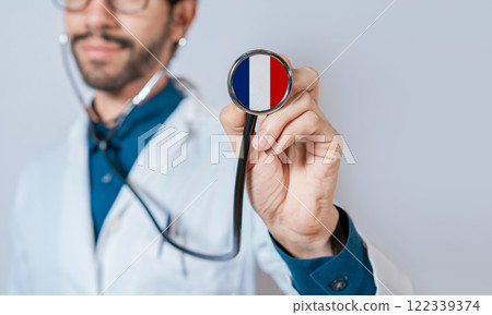 Doctor holding stethoscope with France flag. French Health and Care Concept, France flag on stethoscope 122339374