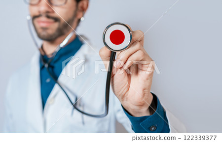 Doctor holding stethoscope with Japan flag. Japanese Health and Care Concept, Japan flag on stethoscope Doctor holding stethoscope with Japan flag. Japanese Health and Care Concept, Japan flag on stethoscope 122339377