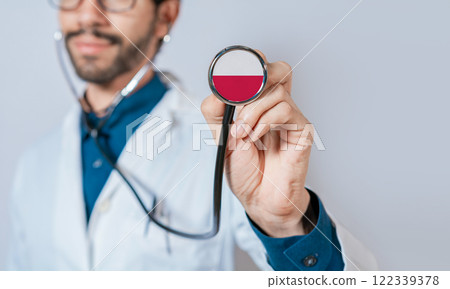 Doctor holding stethoscope with Poland flag. Polish Health and Care Concept, Poland flag on stethoscope Doctor holding stethoscope with Poland flag. Polish Health and Care Concept, Poland flag on stethoscope 122339378