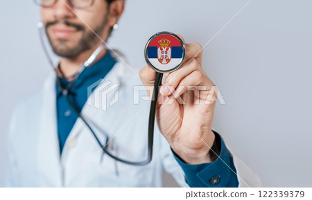 Doctor holding stethoscope with Serbia flag. Serbia Health and Care Concept, Serbia flag on stethoscope Doctor holding stethoscope with Serbia flag. Serbia Health and Care Concept, Serbia flag on stethoscope 122339379