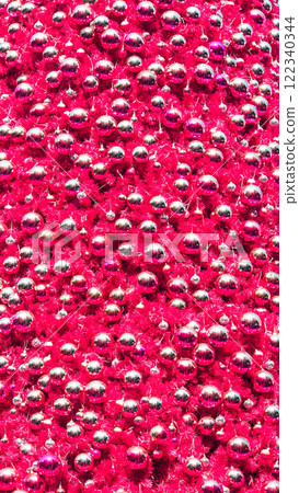 A vibrant close-up of metallic silver and magenta Christmas ornaments densely packed onto bright magenta tinsel, creating a festive and dynamic texture A vibrant close-up of metallic silver and magenta Christmas ornaments densely packed onto bright magenta tinsel, creating a festive and dynamic texture 122340344