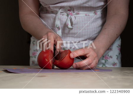 women's hands cut the tomato in half women's hands cut the tomato in half 122340900