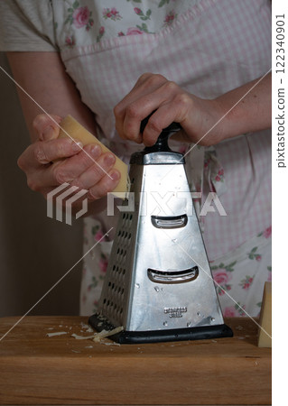 women's hands rub hard cheese on a metal grat women's hands rub hard cheese on a metal grat 122340901