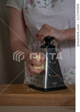 women's hands rub cheese on a metal grat 122340906