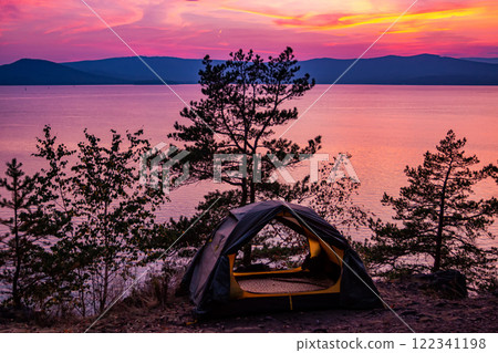 Tent on a hill near the lake against the backdrop of a picturesque sunset Tent on a hill near the lake against the backdrop of a picturesque sunset 122341198