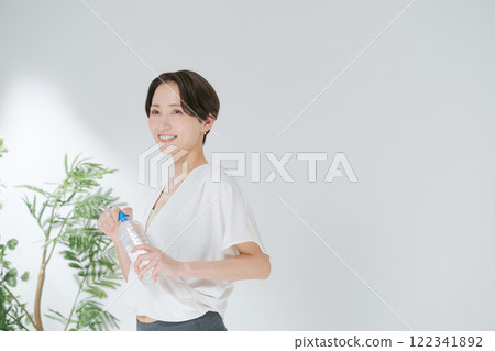 穿著訓練服的女人拿著塑膠瓶水 穿著訓練服的女人拿著塑膠瓶水 122341892