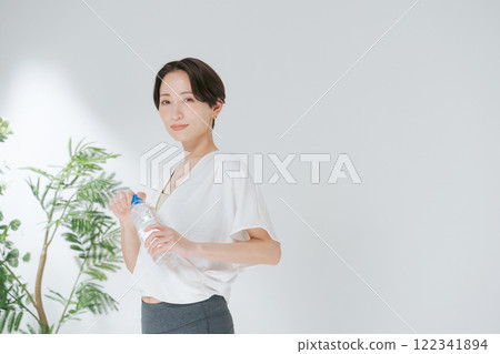 穿著訓練服的女人拿著塑膠瓶水 122341894