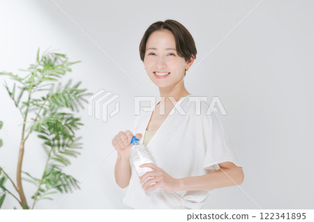 穿著訓練服的女人拿著塑膠瓶水 122341895